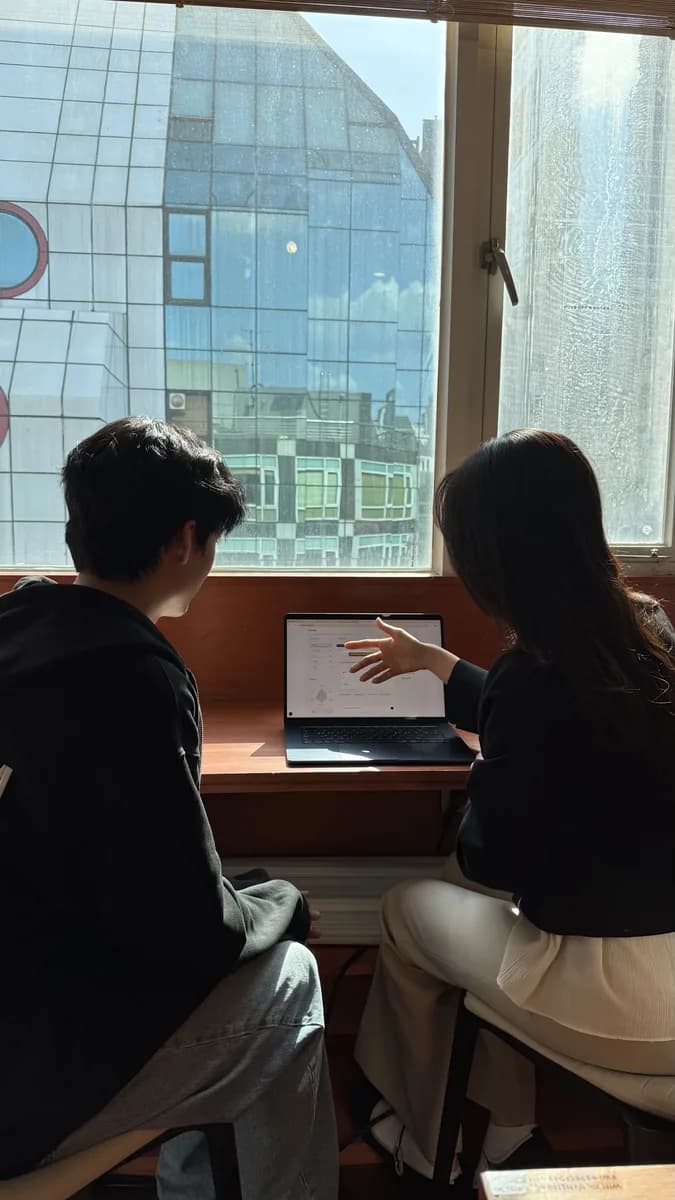 창가 자리에서 멘토와 학생이 노트북을 함께 보는 모습