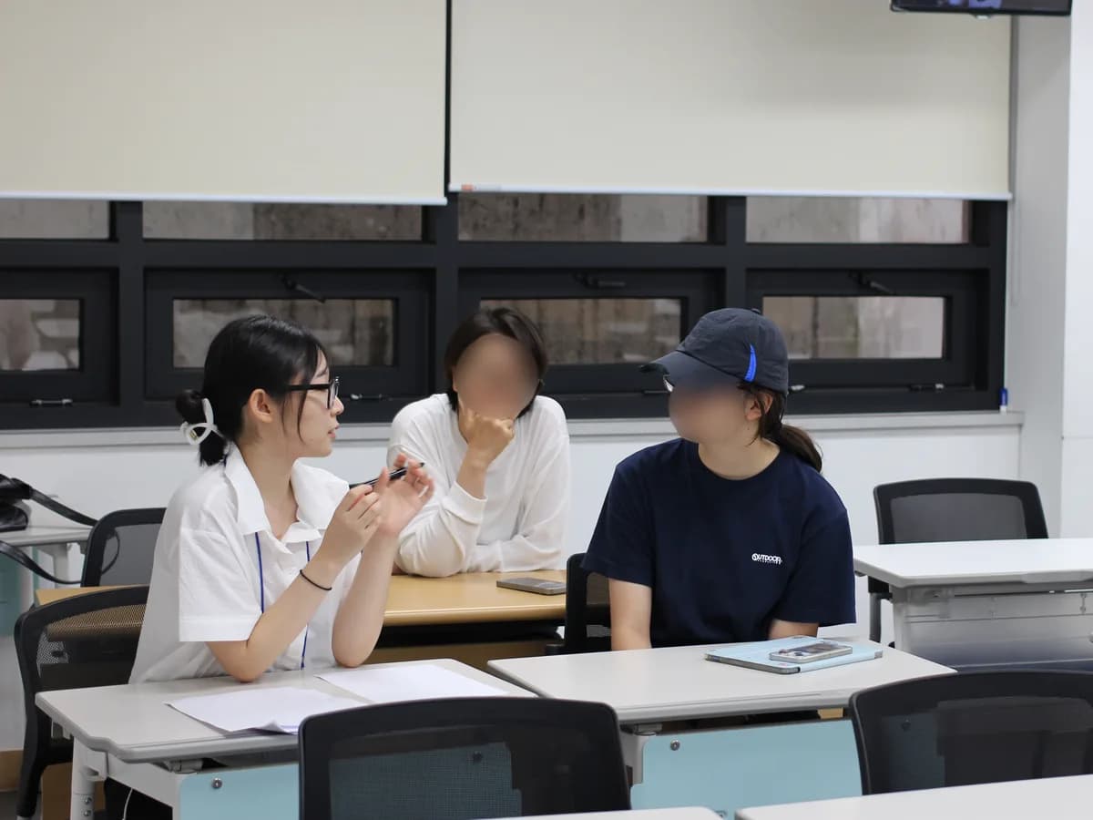 교실에서 멘토가 두 참가자와 마주 앉아 이야기하는 모습