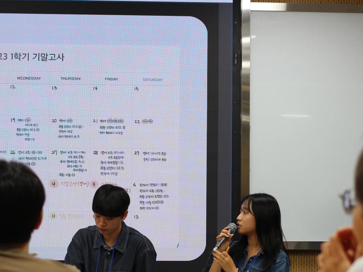 학습 계획표 화면 앞에서 멘토가 마이크로 설명하는 모습